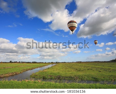 Bright striped balloon flies over the flat plain that is crossed by narrow water channels