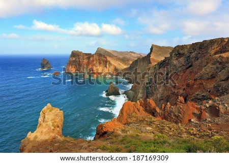 Eastern tip of the island of Madeira. Red and orange rocks cool grow out of foamy waves of the Atlantic Ocean