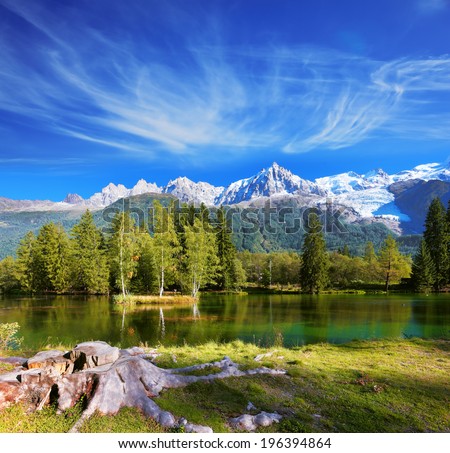 City park in the Alpine resort of Chamonix. Cold lake surrounded by trees and snow-capped mountains