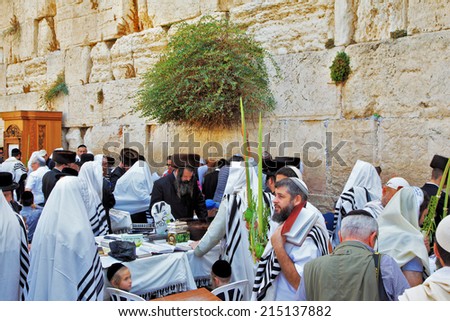 JERUSALEM, ISRAEL - SEPTEMBER 20, 2013: Western Wall of the Temple in Jerusalem. Many religious Jews in traditional white robes gather for prayer. Morning Sukkot.
