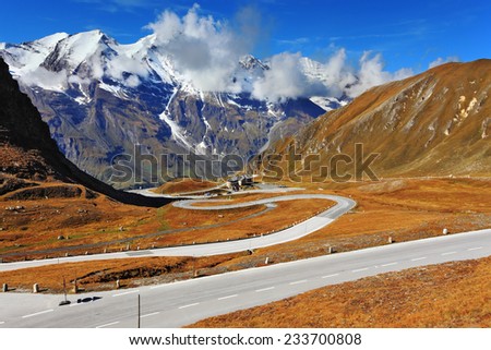 The well-known picturesque specific road in the Austrian Alps - Grossglocknershtrasse. Idealnoye Highway curls highly in mountains. The highest mountain tops are covered with fresh snow