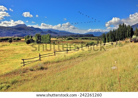 Picturesque rural landscape. Light wood fences are installed on the slopes of the hilly land