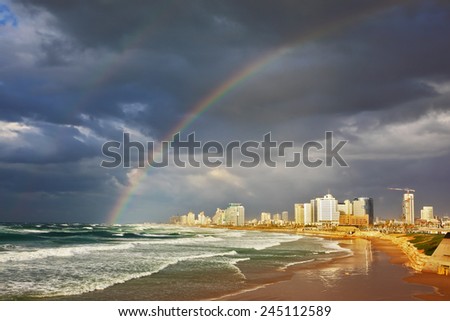 Storm cloud hanging over the sea, gorgeous huge rainbow crossed the sky. Promenade and beach in Tel Aviv