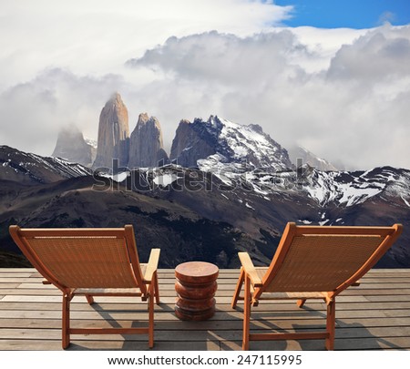 Two comfortable wooden deck chairs are on the platform overlooking the cliffs Torres del Paine