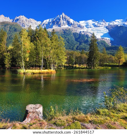 City park in the Alpine resort of Chamonix. Cold lake surrounded by trees and snow-capped mountains.