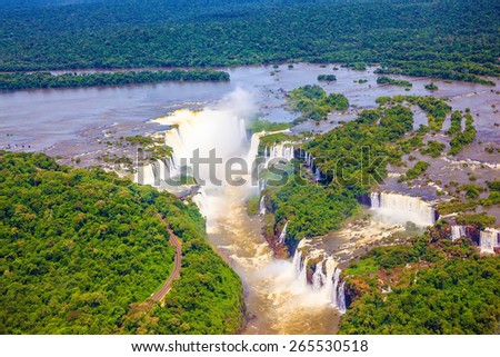 Iguazu River spreads widely among the dense tropical forests. Devil\'s Throat - largest waterfall of the Iguazu Falls. Picture taken from a helicopter