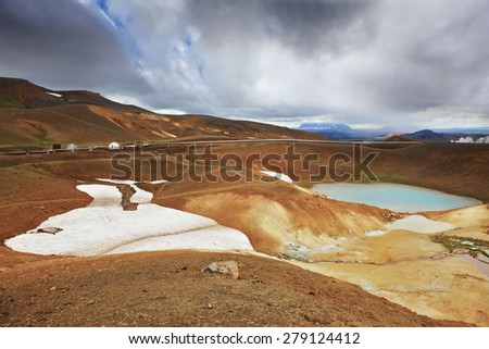July in Iceland. Krafla lake in the crater of an extinct volcano. On the banks are last year\'s snow fields