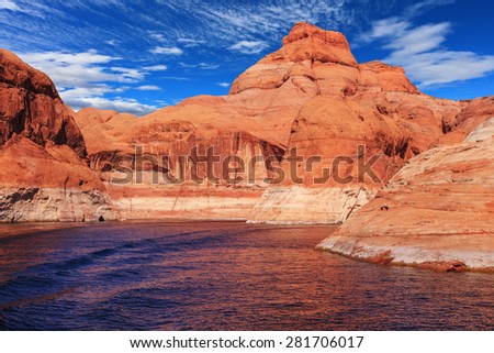 Walk by tourist motor ship on water on sunset. The lake is surrounded with amazing coast from orange sandstone. Picturesque artificial huge reservoir Powell on the river Colorado, USA