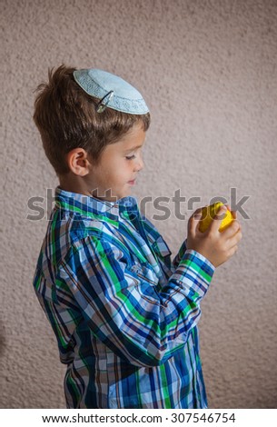 Citrus -  ritual fruit for the Jewish holiday of Sukkot. Beautiful seven year old boy in white knitted skullcap is holding citrus