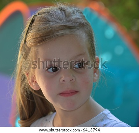 The small serious girl plays to a garden