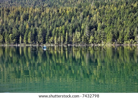 A white boat on the lake surrounded by a dense wood