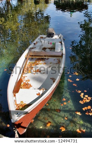 Little boat Canal and boat, covered with autumn leaves, a bright sunny noon