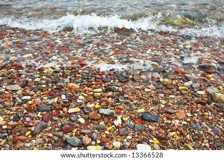 Fine stones and a pebble filled in by water of a surf on a southern beach