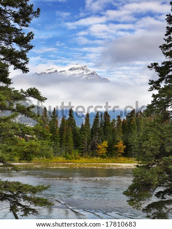 The mountain river with the transparent water and snow-covered mountain  on a background