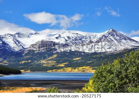 Northern landscape - cold lake, snow mountains and yellow bushes