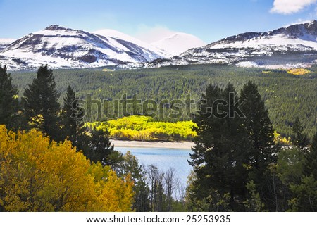 Northern landscape - cold lake, snow mountains and yellow bushes