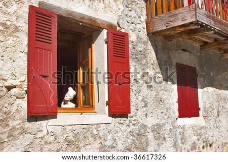 A head of a doll of a dummy in a window of the ancient stone house, shined by the sun
