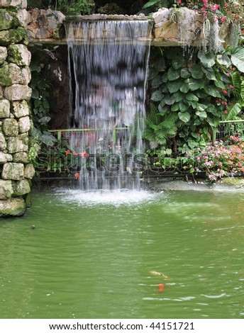 Magnificent decorative waterfalls with gold small fishes in tropical park
