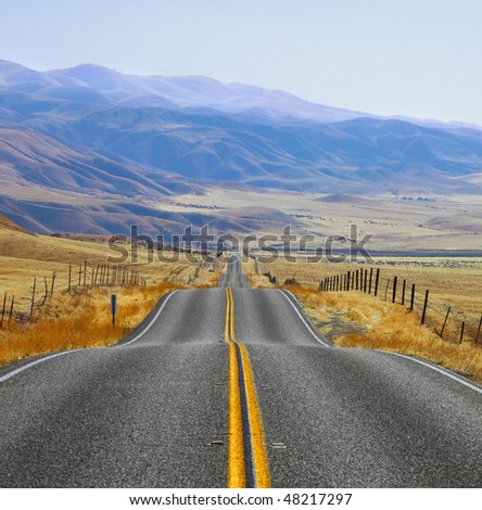 The Californian prairie and mountains in the distance, autumn day. Magnificent American road and fencings