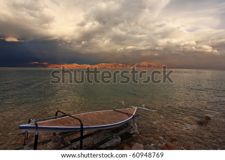 Off-season at the Dead Sea in Israel. The clouds, close all the sky, and board sailing, laid up
