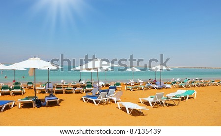 Sunny spring day on the beach luxury hotel on the Dead Sea in Israel. A few swimmers in the water, take the sea baths