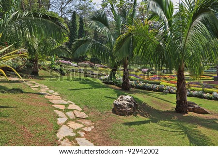 Huge picturesque landscape park in Thailand. Palm trees and intricately decorated flower beds