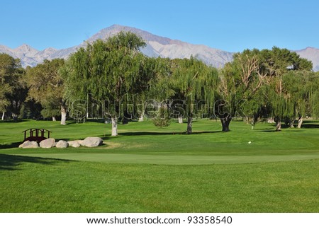 The picturesque golf course in Bishop, California. Beautiful grassy lawn, large trees and a small bridge over a stream