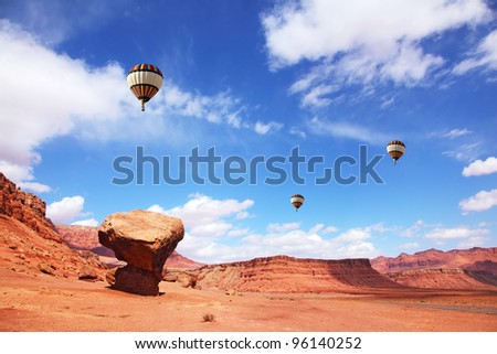 Huge balloons with the passenger basket flying over the picturesque cliffs of red sandstone