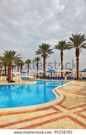 Winter in the Dead Sea. The picturesque swimming pool, palm trees and beach umbrellas