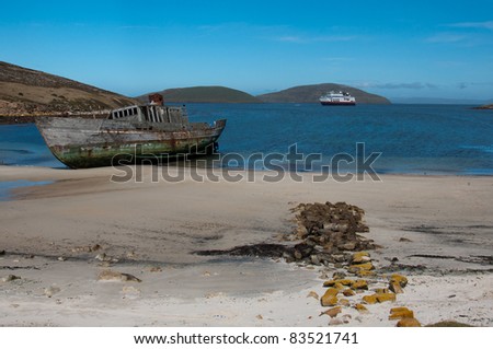 Shipwreck on the beach in Antarctica. A derelict sealing boat washed ashore with modern cruise ship in background.