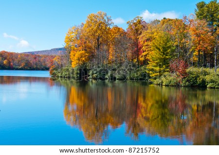 Lake reflections of fall foliage. Colorful autumn foliage casts its reflection on the calm waters of a North Carolina lake along the Blue Ridge Parkway.