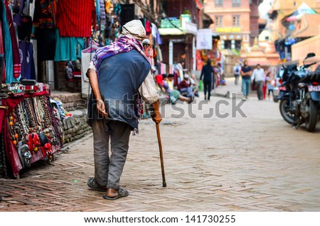 Poor old man walking with stick in exotic asian street, Nepal