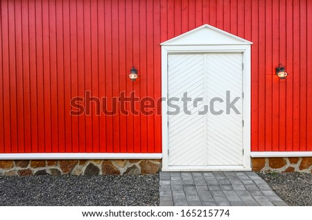 Red wooden wall and front white doors with two porch lamps