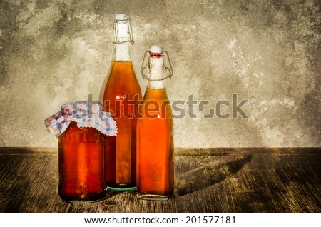 Bottles filled with yellow syrup and jam on kitchen table in vintage style
