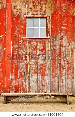 Red old barn with two windows and lonely bench - vertical