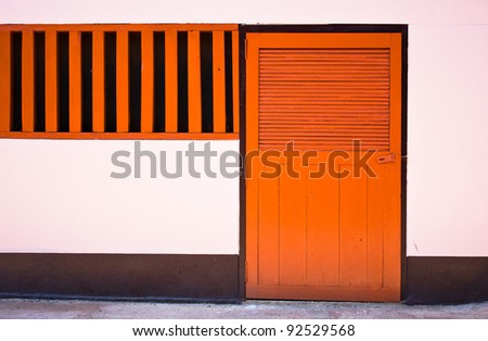 orange door closed on pink wall.