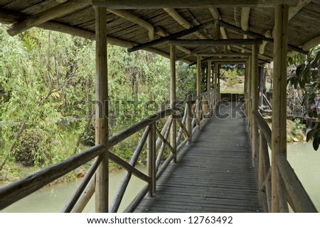 The corridor of wooden walk bridge over lake in garden