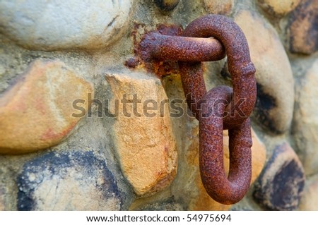 Rusty chain hanging on old stone wall