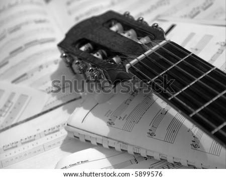 Head and neck of an acoustic guitar with sheet music