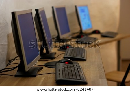 Four computer terminals on a desk in a row