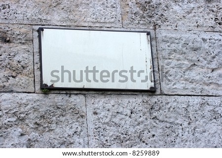 Empty signboard on a stone wall. Add your own text!