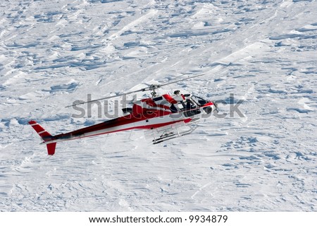 Rescue helicopter flying above snow covered mountains