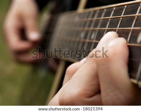 Fingers of a guitar player, shallow DoF, socus is on the finger holding the note
