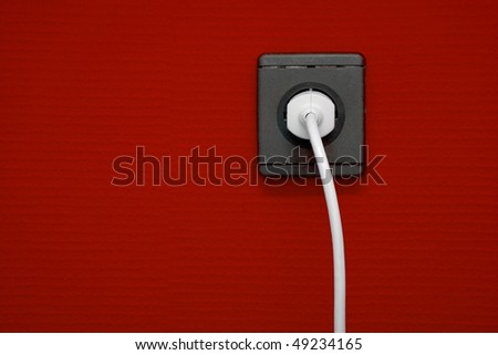 Electric outlet on red wall with cable connected