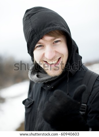 Hooded man in winter showing thumbs up
