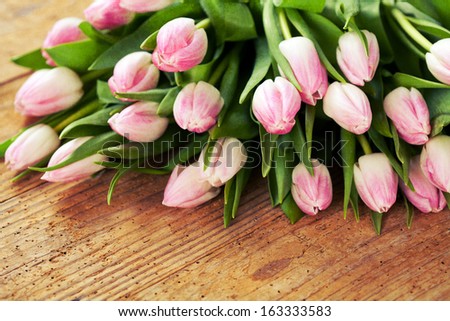 Bunch of pink tulips on wooden background, textured