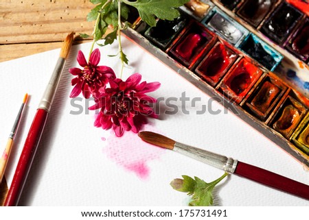 Watercolor paint box, flowers and brushes for painting