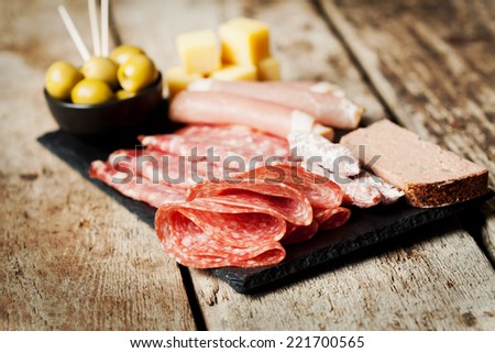 Charcuterie assortment and olives on wooden background