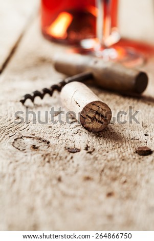 Wine cork and corkscrew on wooden table, wine bottle and glass on the background
