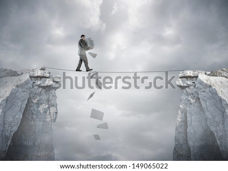 Business Balance - A Businessman Carrying Paperwork Walking Over A Tight Rope.
